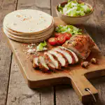 baked chicken for tacos on cutting board with toppings