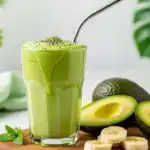 Vibrant natural green avocado smoothie recipe in a clear glass with chia topping