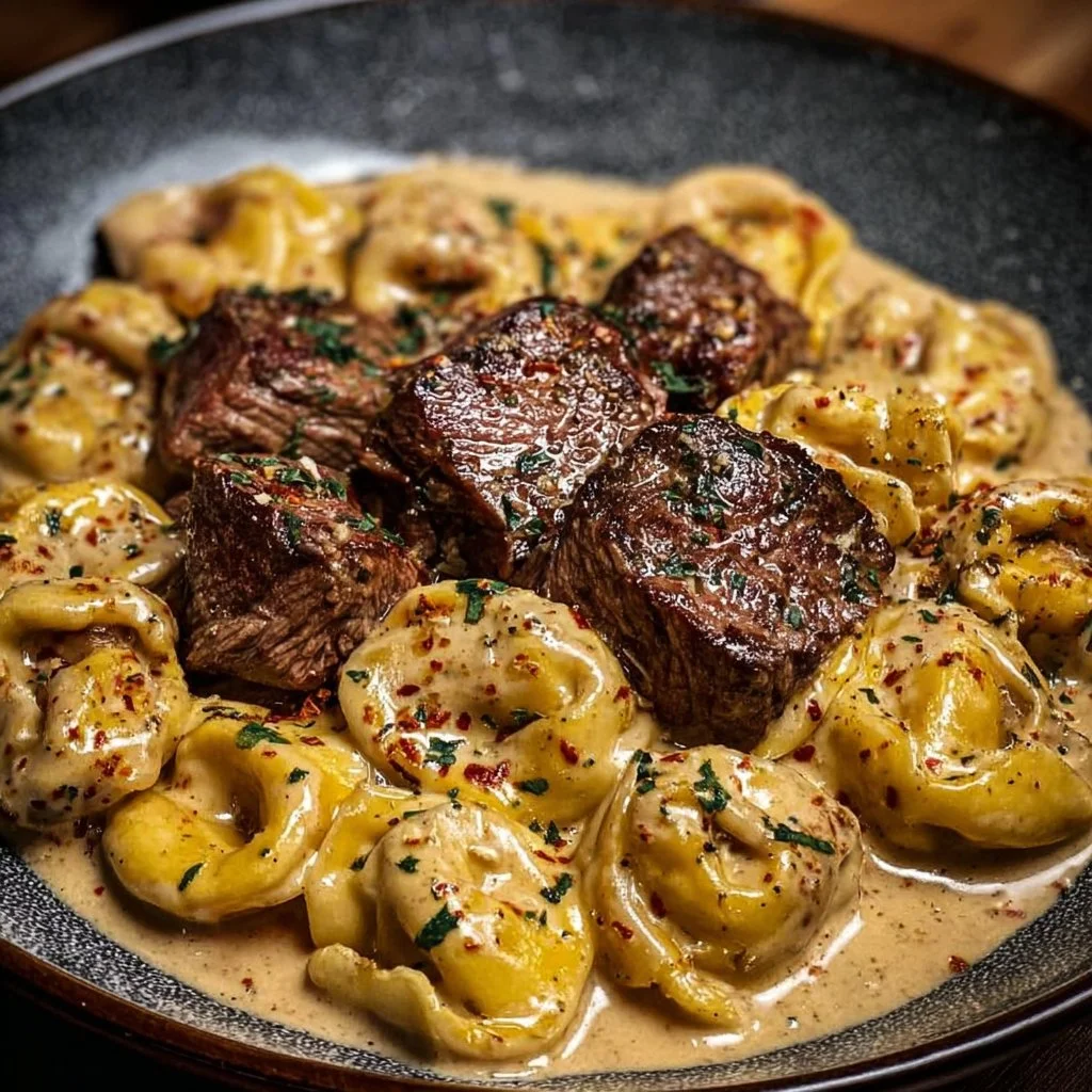 Creamy garlic steak tortellini served in a bowl with herbs