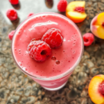 Creamy Raspberry Peach Smoothie in a Glass Topped with Fresh Raspberries